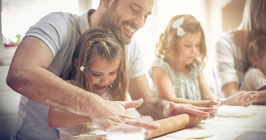 A father prepares a meal with his children. 